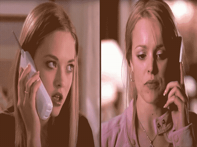 Two Women Are Talking On Their Cell Phones And One Has A Ring On Her Finger GIF