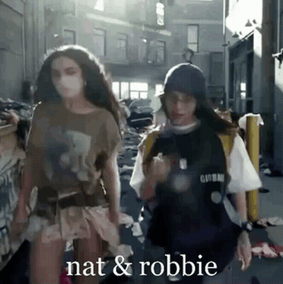 Two Women Are Walking Down A Street And The Words Nat And Robbie Are Visible GIF