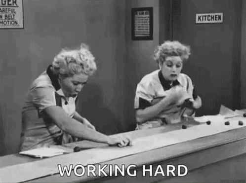 Two Women Are Working Hard On A Conveyor Belt In A Black And White Photo . GIF
