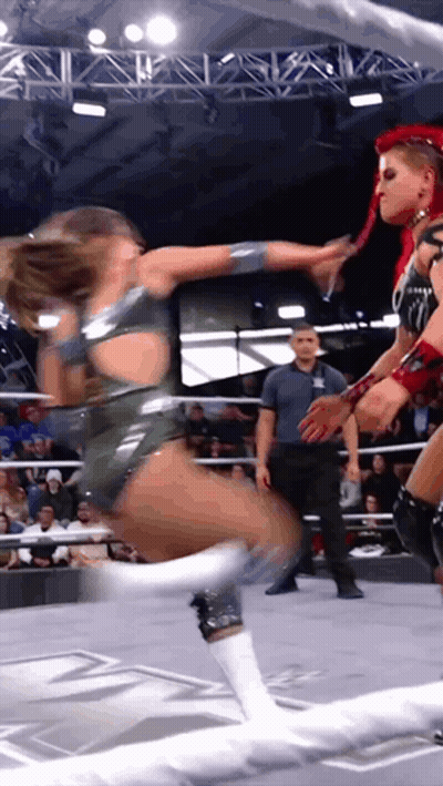 Two Women Are Wrestling In A Ring While A Referee Watches GIF
