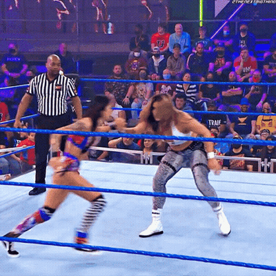 Two Women Are Wrestling In A Ring With A Referee And A Crowd Behind Them With A Shirt That Says Train On It GIF