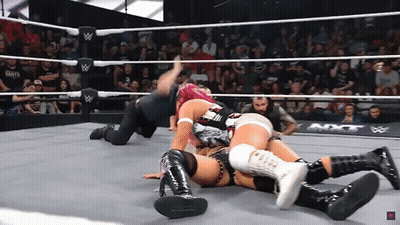 Two Women Are Wrestling In A Wrestling Ring With A Crowd Watching . GIF
