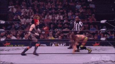 Two Women Are Wrestling In A Wrestling Ring With A Referee In The Background . GIF