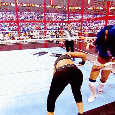 Two Women Are Wrestling In A Wrestling Ring With A Referee Watching . GIF