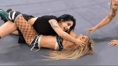 Two Women Are Wrestling On A Wrestling Mat With The Letters N On The Bottom Right GIF