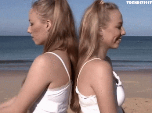 Two Women Back To Back On Beach With Trendizissy GIF