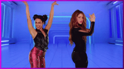 Two Women Dancing In Front Of A Sign That Says Meow GIF