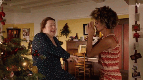 Two Women Dancing In Front Of Christmas Tree GIF