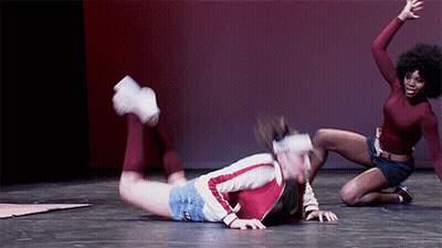 Dos mujeres bailando en el escenario, una arrodillada, una acostada GIF