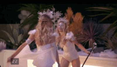 two women dressed as snowflakes are dancing together in a dark room .