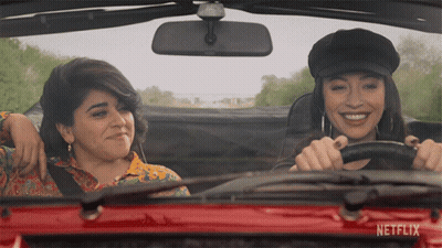 Two Women Driving Red Car With Netflix On Windshield GIF