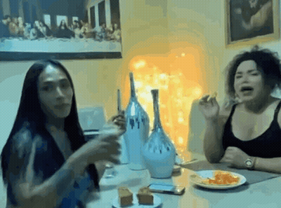 Two Women Eating At Table In Front Of Last Supper Painting GIF