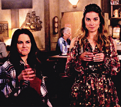 Two Women Holding Drinks At Bar GIF