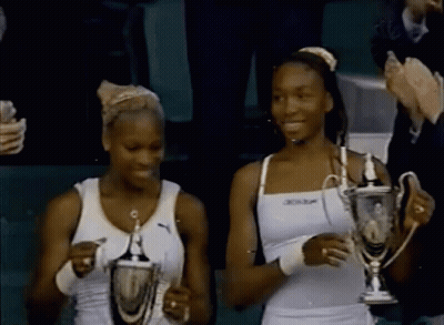 Two Women Holding Trophies With Dunlop On Top GIF