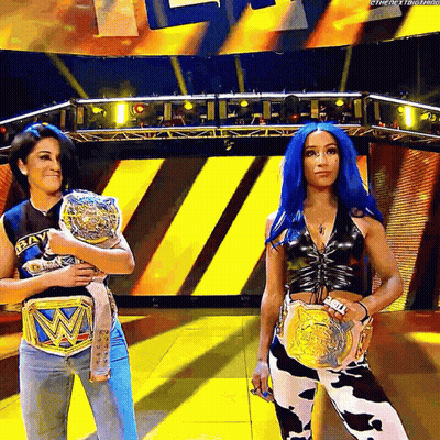 Two Women Holding Wrestling Belts On Stage GIF