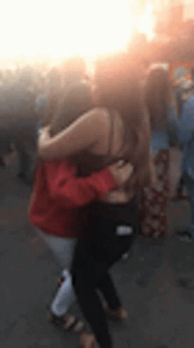 Two Women Hugging In Blurry Crowd GIF