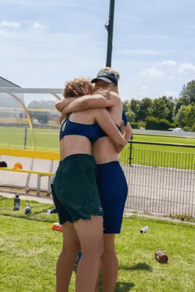 Two Women Hugging In Field With Water Bottle GIF