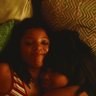 Two Women Hugging On Bed With Patterned Pillow GIF
