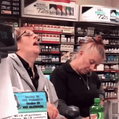 Two Women In A Store With A Sign That Says No Alcohol On It GIF