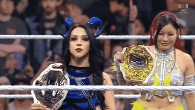 two women in a wrestling ring holding trophies with the letters w in the background