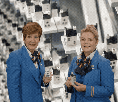 Two Women In Blue Uniforms Holding Miniature Houses GIF