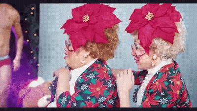 Two Women In Christmas Costumes Side By Side GIF