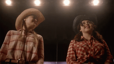 Two Women In Cowboy Hats And Plaid Shirts Looking Up GIF