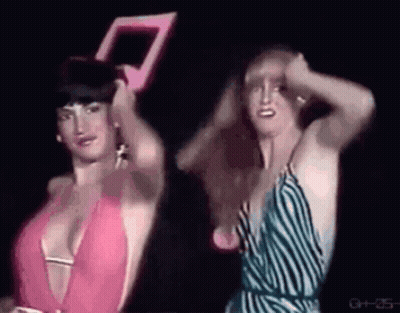Two Women In Dark Room One Holding Mirror GIF