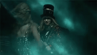 Two Women In Dark Room One Wearing Top Hat GIF