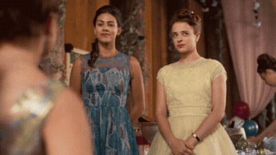 Two Women In Dresses Are Standing Next To Each Other In A Room GIF
