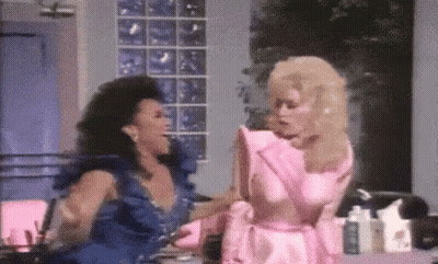 Two Women In Dresses Standing And Talking GIF