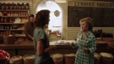 Two Women In Front Of Current Prices Sign GIF