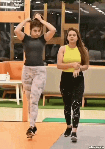Two Women In Gym One Adjusting Hair GIF