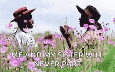 Two Women In Hats Are Standing In A Field Of Flowers . GIF