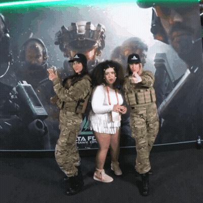 Two Women in Military Uniforms in Front of Delta Force Hawk Ops Poster