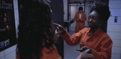 Two Women In Orange Jumpsuits In Front Of Laboratory Poster GIF