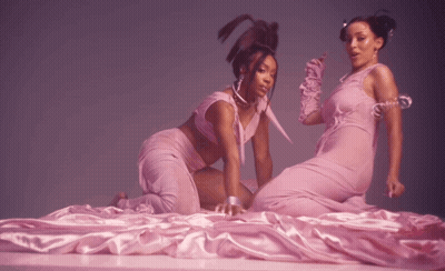 Two Women In Pink Dresses Laying On Bed GIF
