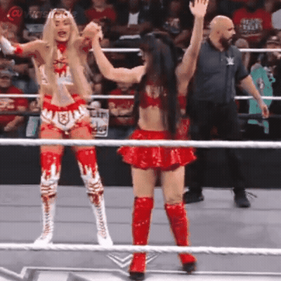 Two Women In Red Wrestling Outfits Are Standing In A Ring . GIF