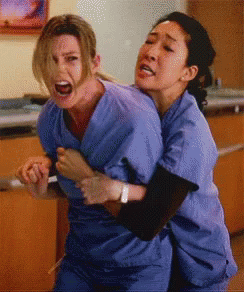 Two Women In Scrubs Hugging With One Screaming GIF