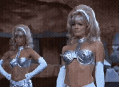 Two Women In Silver Bikinis And White Gloves In Cave GIF