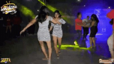 Two Women In Striped Dresses Are Dancing On A Dance Floor In A Club . GIF