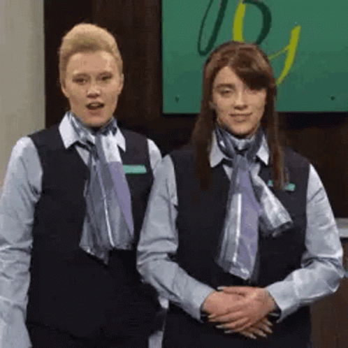 Two Women In Uniforms And Scarves In Lobby GIF