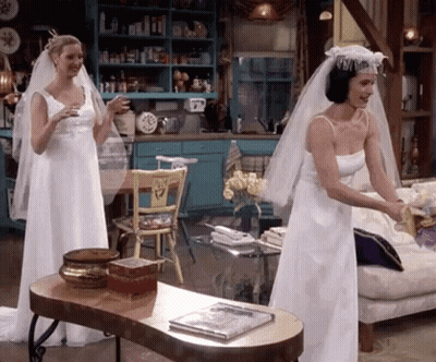 Two Women In Wedding Dresses Standing Next To Each Other GIF