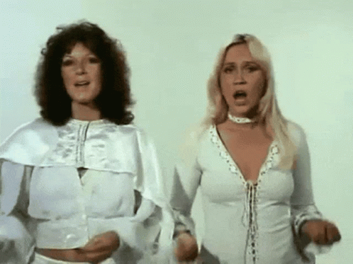 Two Women In White Dresses Are Standing Next To Each Other With Their Mouths Open GIF