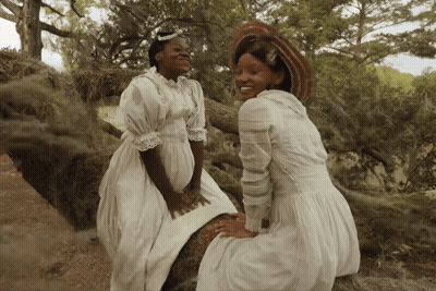 Two Women In White Dresses Sitting Next To Each Other GIF