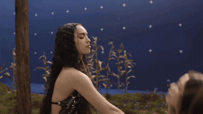Two Women Kissing Each Other In Front Of A Blue Background GIF