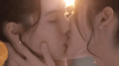 Two Women Kissing In Front Of Light Bulb GIF