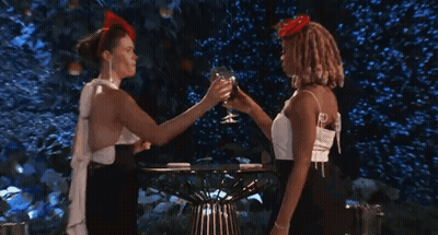 Two Women Kissing While Drinking From Glasses GIF