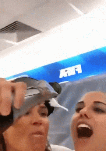 Two Women Laughing In Front Of A Sign That Says Rf GIF