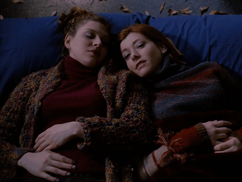 Two Women Laying Next To Each Other With Teach Me GIF